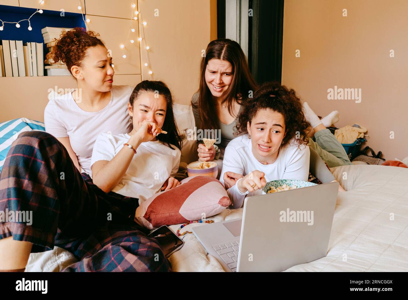 Amici femminili che fanno volti mentre guardano un film su un notebook a casa Foto Stock