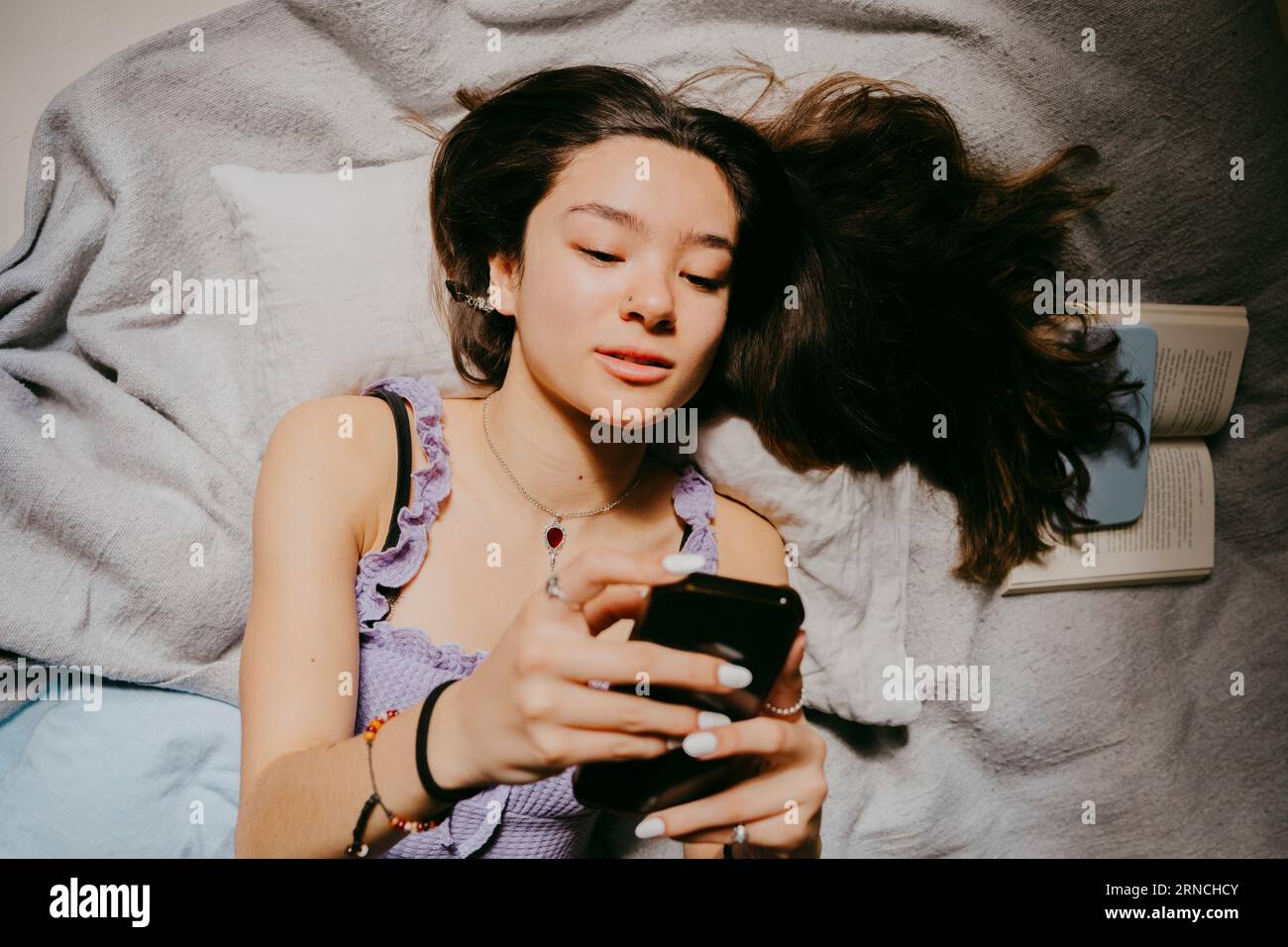 Direttamente sopra la foto di una donna che usa uno smartphone mentre si trova a letto a casa Foto Stock