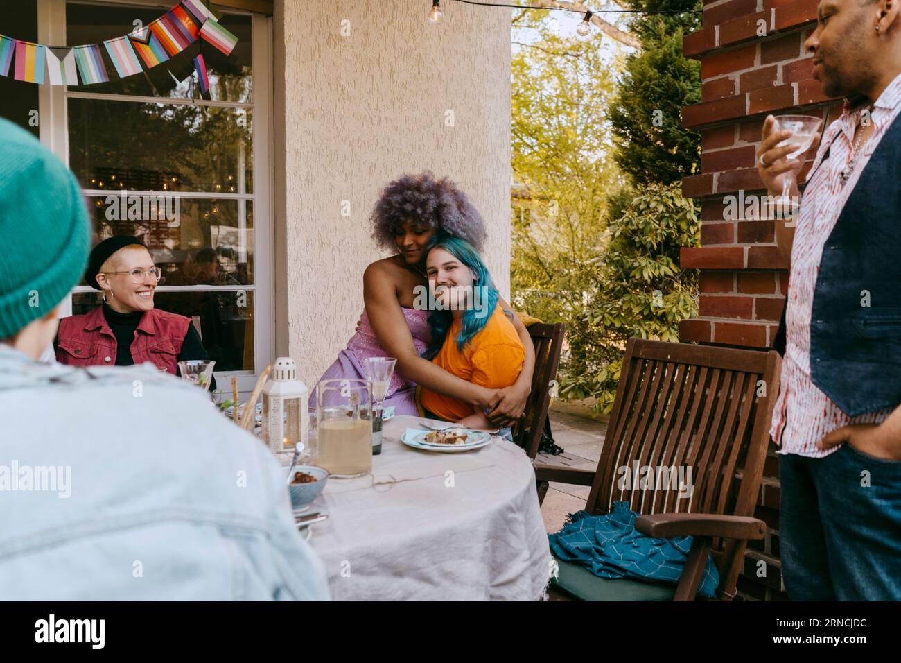 Amici LGBTQ che si abbracciano a vicenda durante la cena in cortile Foto Stock