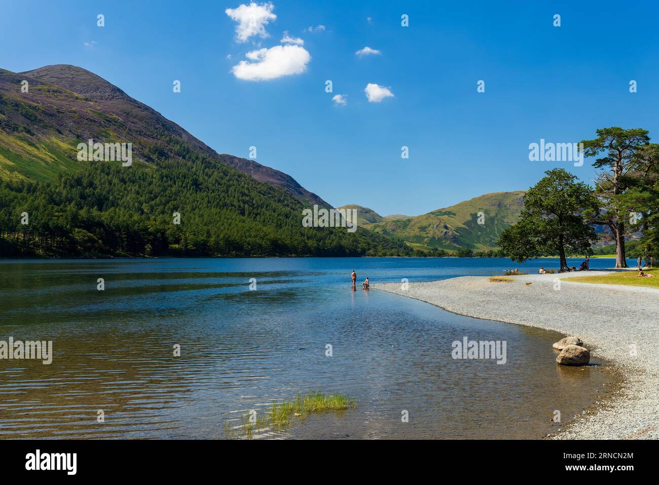 Nuota su un grande e tranquillo lago circondato da montagne in una calda giornata estiva Foto Stock