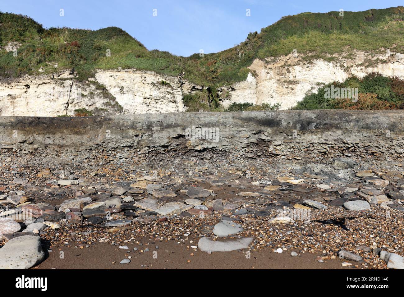 Strati di rifiuti di miniere di carbone e altri detriti industriali che vengono lentamente erosi e lavati via dal mare sulla Blast Beach, Durham Heritage Coast Foto Stock