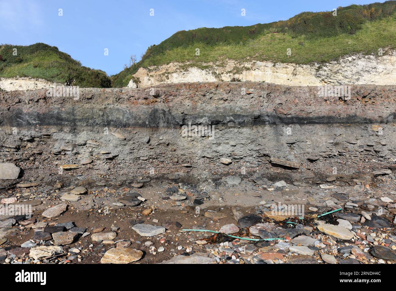 Strati di rifiuti di miniere di carbone e altri detriti industriali che vengono lentamente erosi e lavati via dal mare sulla Blast Beach, Durham Heritage Coast Foto Stock