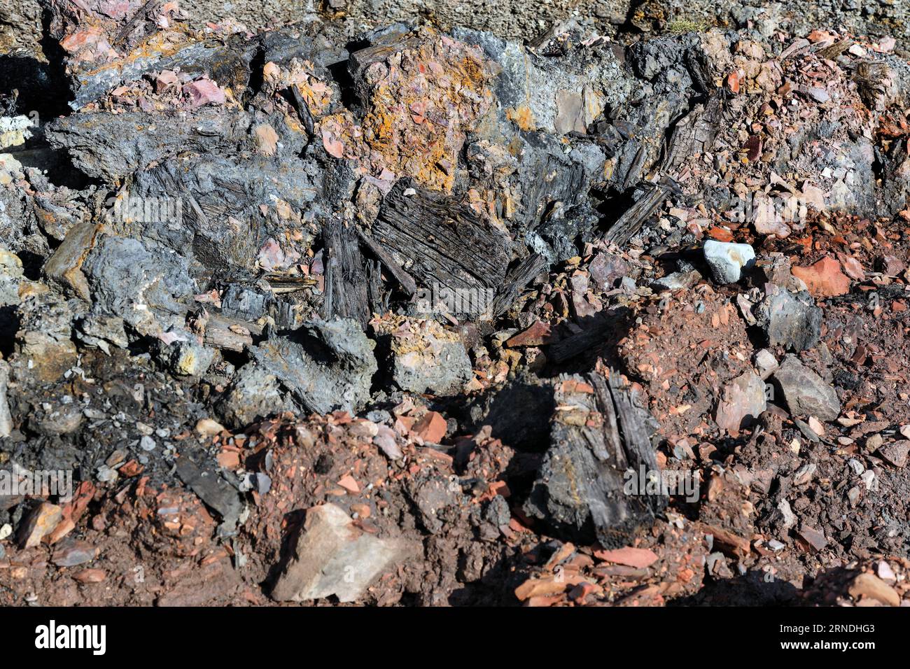 Strati di miniere di carbone colorate e rifiuti di altoforni insieme ad altri detriti industriali che vengono lentamente erosi e lavati via dal mare sul Foto Stock