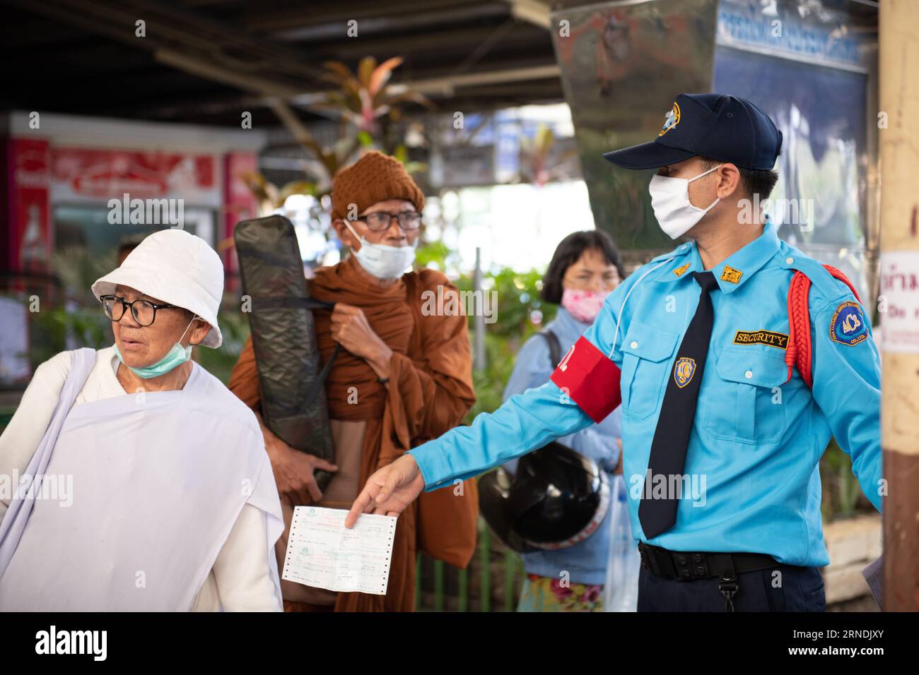 In questa ripresa mirata, un assistente di piattaforma tiene un biglietto mentre assiste un passeggero alla stazione ferroviaria Hua Lamphong di Bangkok. Foto Stock