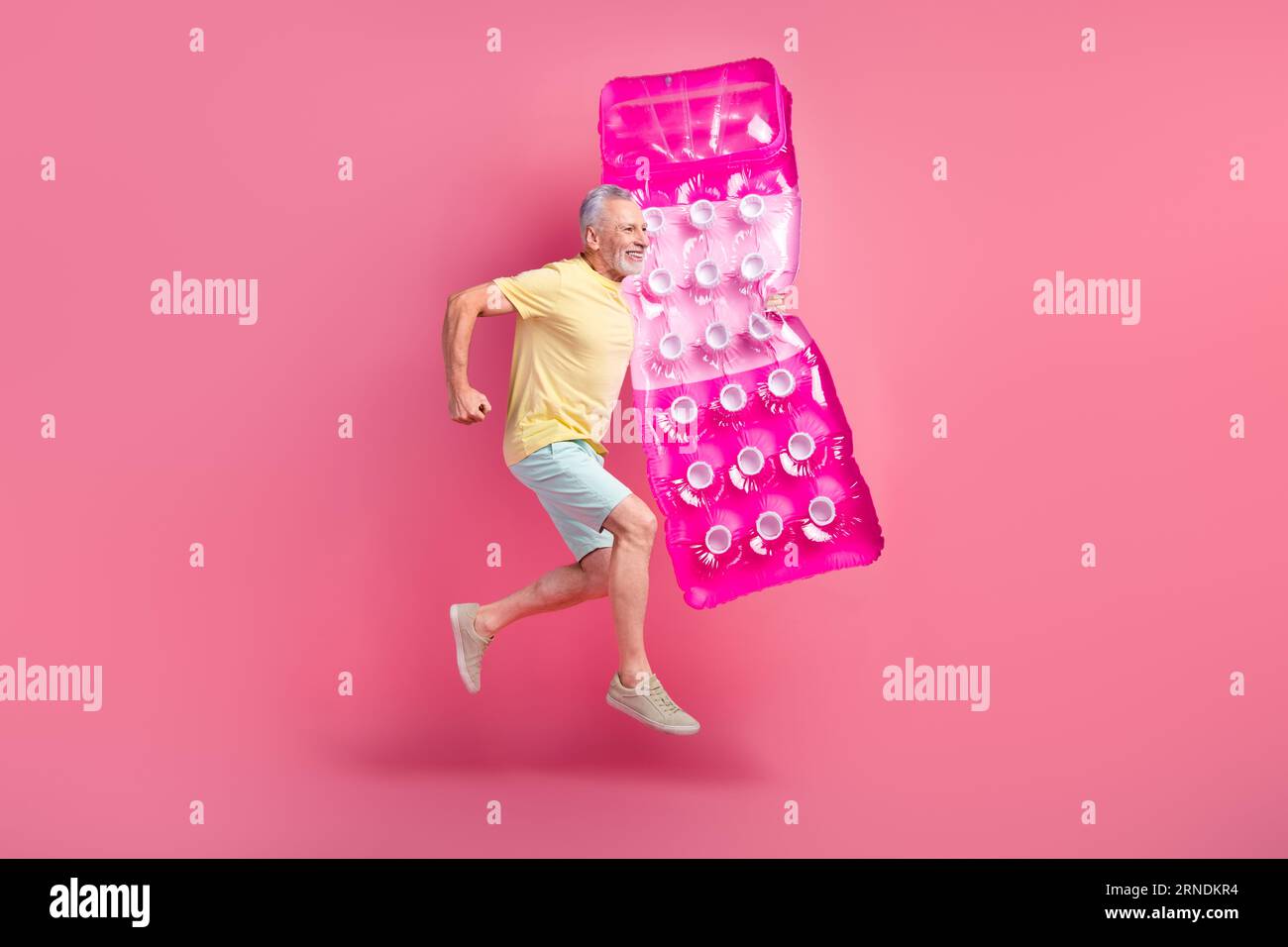 Immagine fotografica a grandezza naturale di un energico pensionato che fa saltare il materasso ad aria che nuota sembra interessato isolato su sfondo rosa Foto Stock