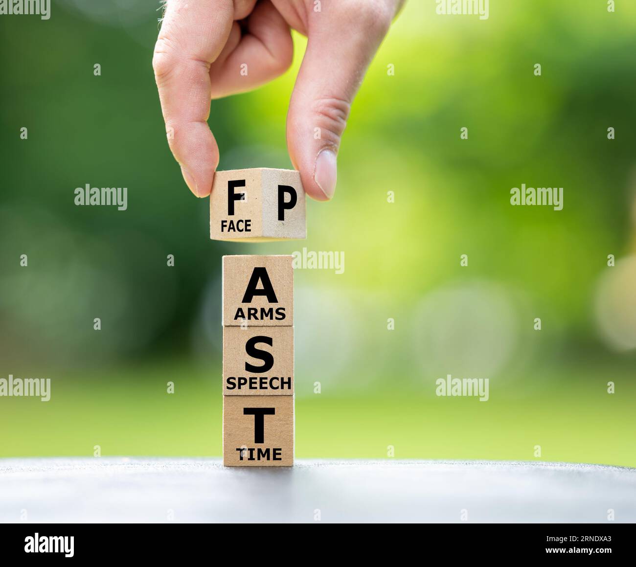 Una pila di cubi di legno forma l'espressione VELOCEMENTE. FAST sta per "caduta del viso", "debolezza del braccio", "difficoltà di linguaggio" e "tempo di chiamare emergenc" Foto Stock