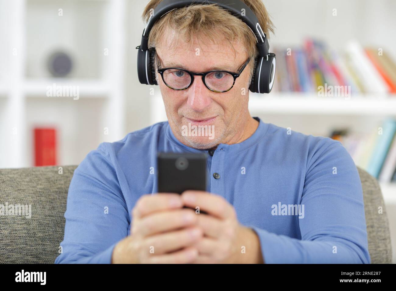 cheerful mature man listening to music from smartphone Foto Stock