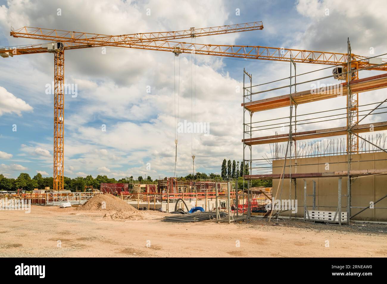 l'area in costruzione con gru gialle e case in costruzione è un progetto di insediamento immobiliare immobiliare che diventa reale con terra marrone e sporco i. Foto Stock
