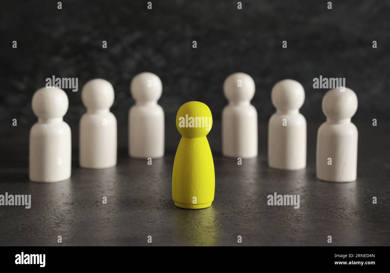 Leadership nel business o concetto di team manager con un leader del pedone di legno giallo che spicca e guida tra gli altri su sfondo grigio scuro. Foto Stock