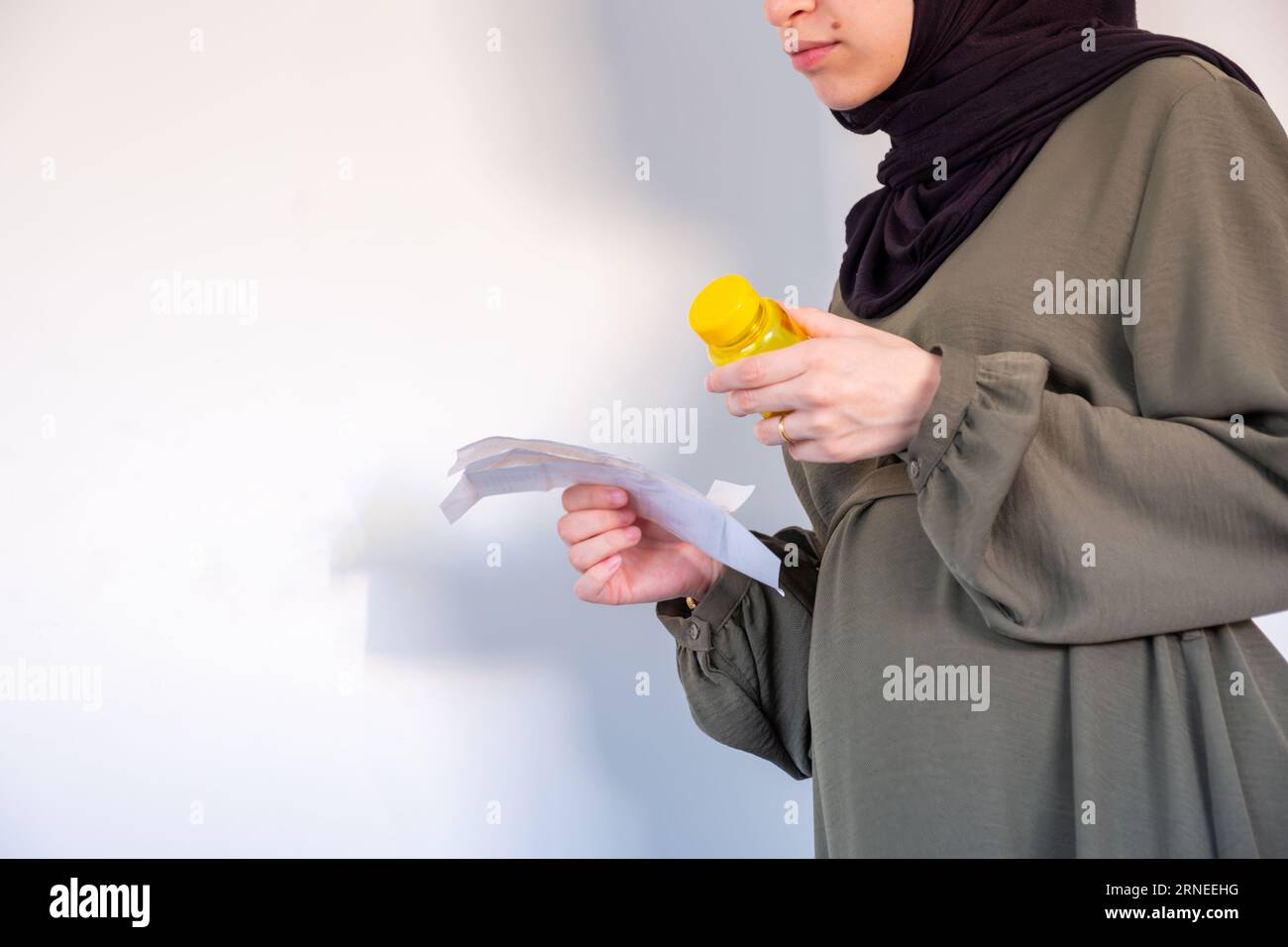 Supplemento di tenuta femminile incinta con esso è conto su sfondo bianco Foto Stock