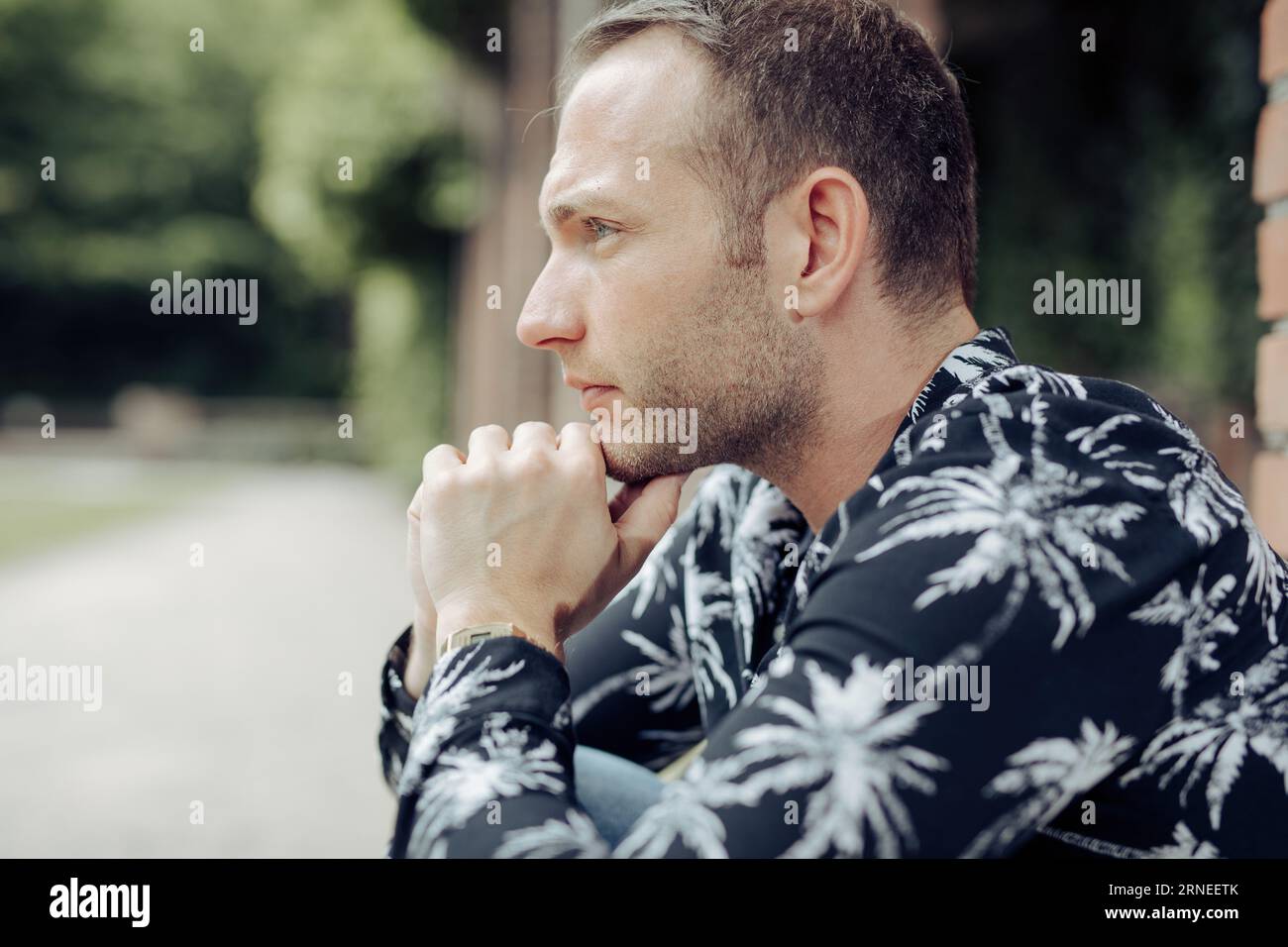 l'uomo scettico con le mani sul mento è all'aperto e sembra attento ed esprime dubbi Foto Stock