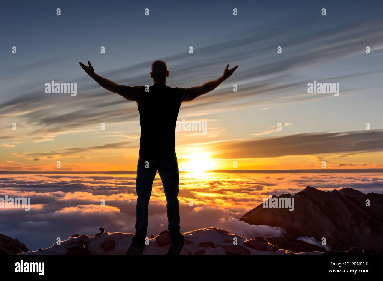 silhouette di uomo in piedi e stendere la mano sulla cima della montagna per godersi il cielo colorato Foto Stock