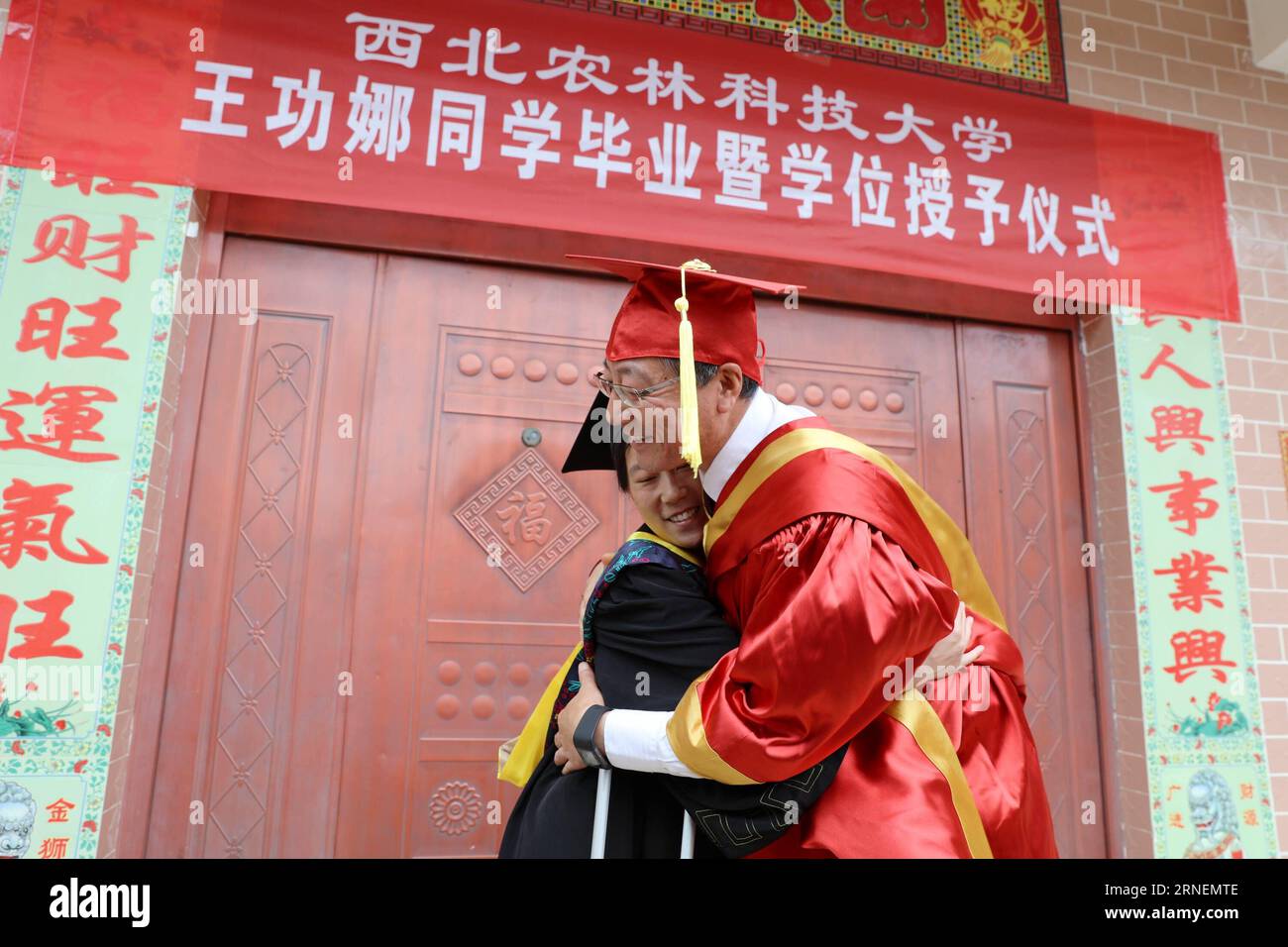 (160629) -- SHANGLUO, 29 giugno 2016 -- Sun Qixin (R), presidente della Northwest A&F University, dà un abbraccio a Wang Gongna durante una speciale cerimonia di laurea tenutasi nella sua casa di Zhongshan Village, contea di Zhashui, provincia dello Shaanxi della Cina nord-occidentale, 26 giugno 2016. Wang Gongna è diventata una studentessa universitaria del college di enologia della Northwest A&F University nel 2010 e purtroppo ha avuto lesioni al midollo spinale in un incidente stradale nell'estate del 2013, che le ha reso impossibile continuare i suoi studi nel campus. Con il sostegno dell'università, Wang ha completato con successo i suoi studi online Foto Stock