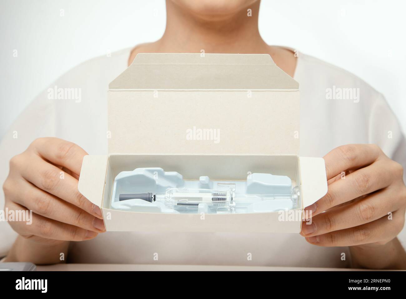 mani femminili che tengono la confezione con siringa di medicina curativa pronta per l'iniezione Foto Stock