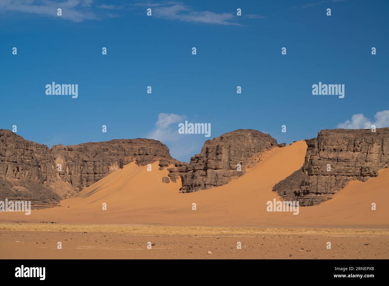 Vista nel deserto del Sahara di Tadrart rouge tassili najer nella città di Djanet, Algeria. Sabbia arancione colorata e montagne rocciose Foto Stock