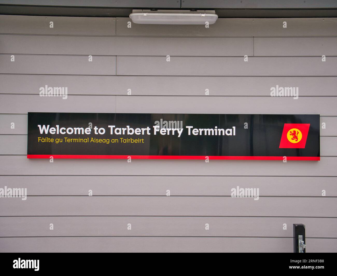 Un cartello di benvenuto rettangolare con logo aziendale presso il terminal dei traghetti Tarbert sull'isola di Harris nelle Ebridi esterne, Scozia, Regno Unito Foto Stock