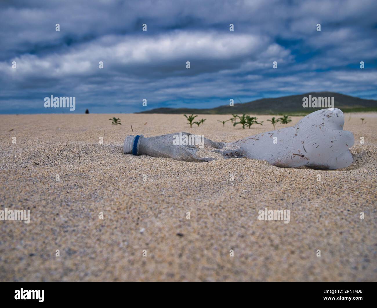 Una bottiglia d'acqua di plastica vuota e scartata sulle sabbie incontaminate di Luskentyre Beach sull'isola di Harris nelle Ebridi esterne, Scozia, Regno Unito - marin Foto Stock
