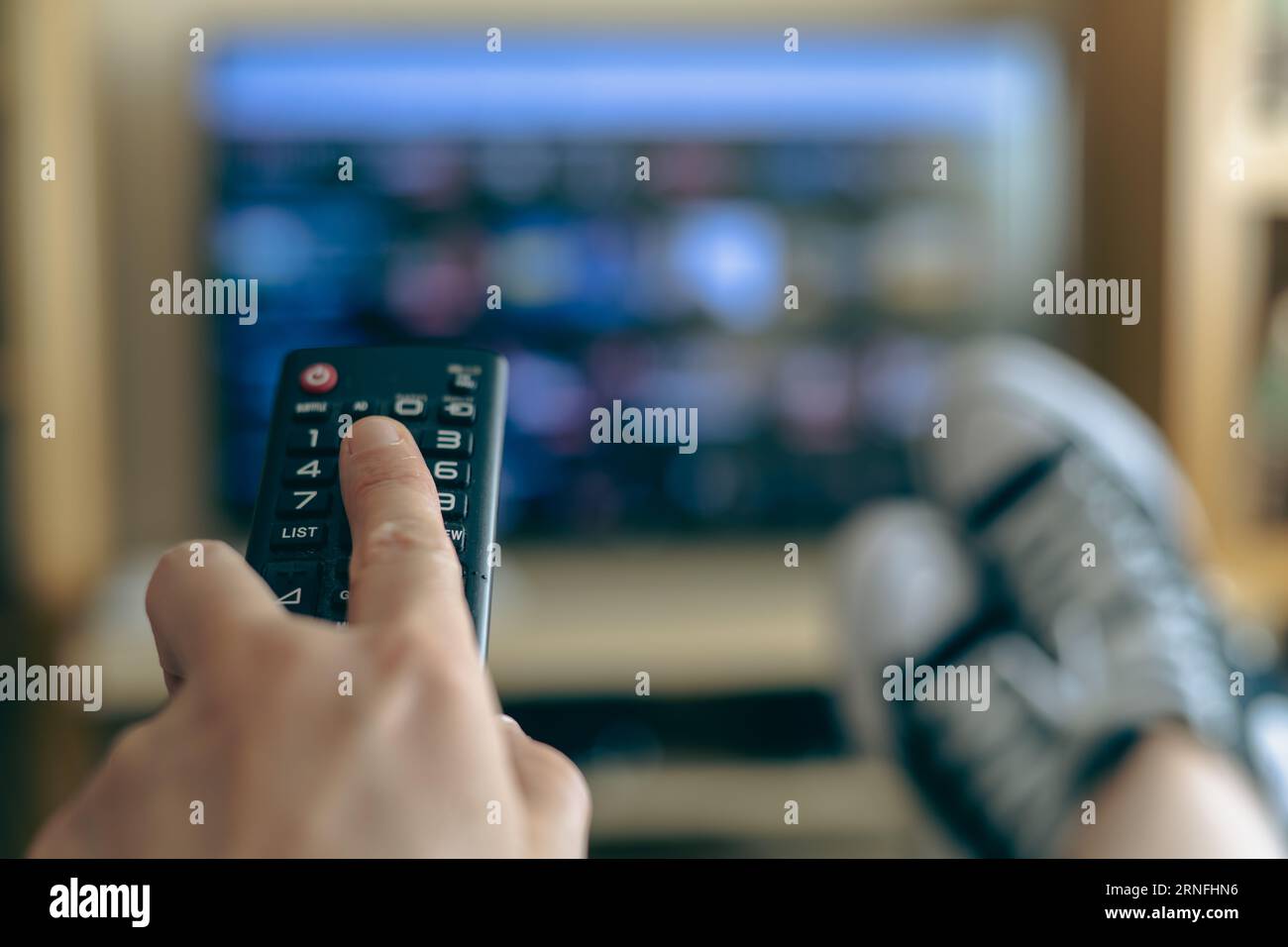 Persona irriconoscibile che si rilassa a casa guardando la TV. Visualizza servizi di streaming per l'intrattenimento sul TV. Scelta di serie TV e film Foto Stock