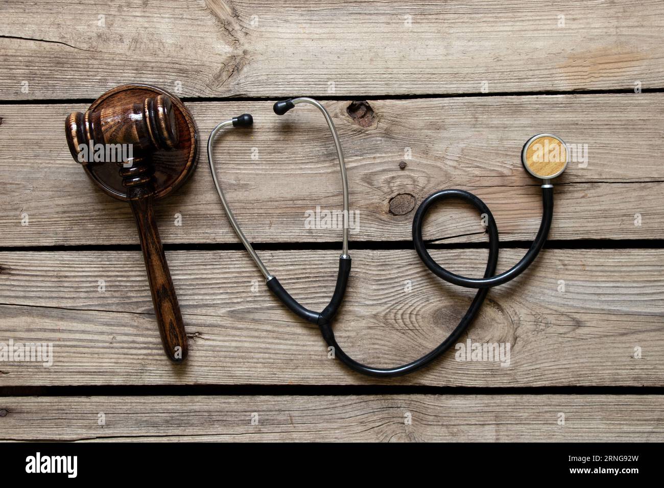 Stetoscopio e il martelletto del giudice giacciono su uno sfondo di legno, tribunale medico, legge e giustizia Foto Stock