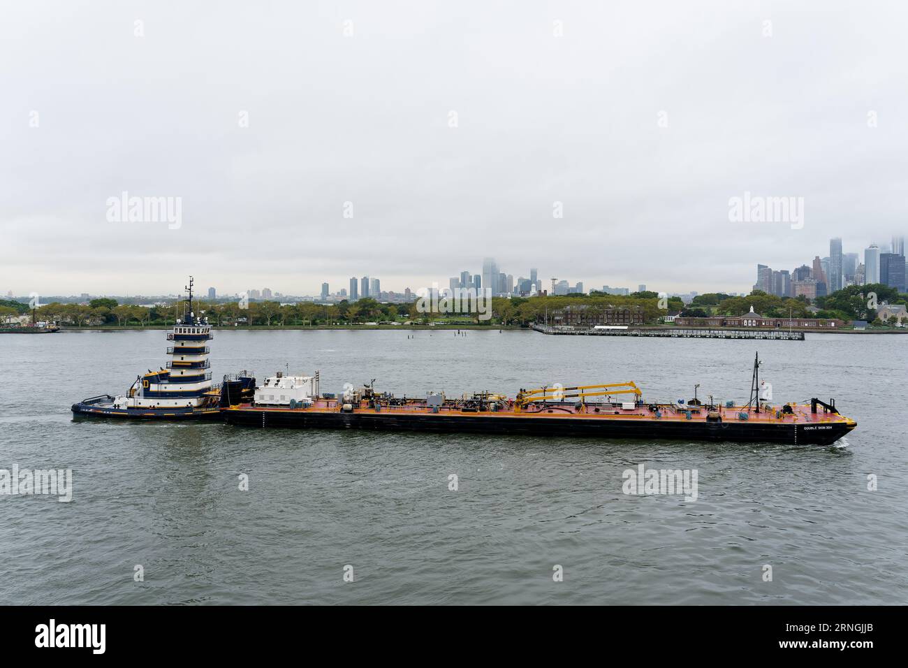 Brooklyn, NY - 30 agosto 2023: Discovery Coast Pusher Tug con la chiatta a doppio scafo 304 a doppia pelle a olio su Buttermilk Channel di mattina presto. Foto Stock