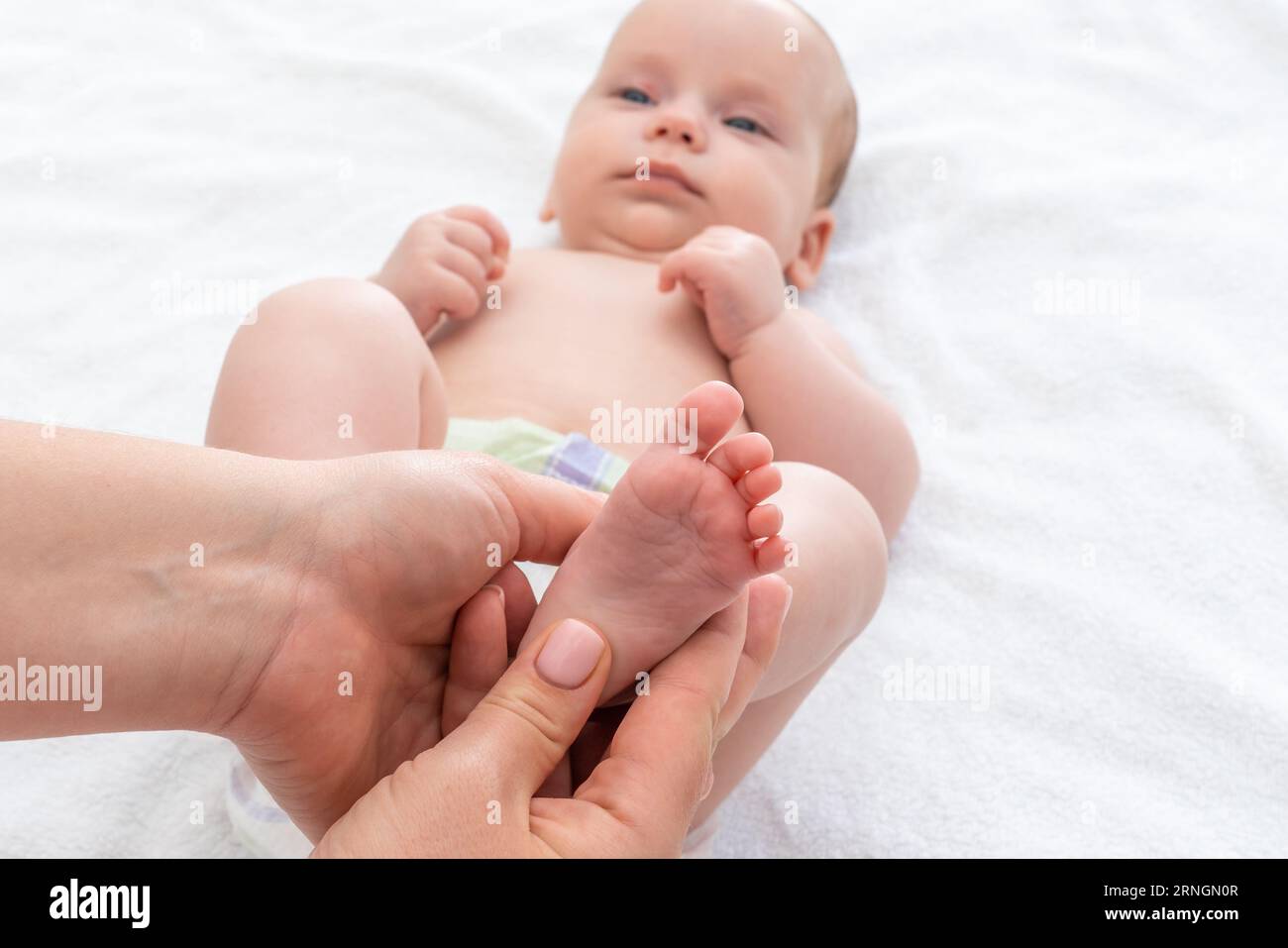 Il tocco della madre mentre massaggia i piedi del bambino. Concetto di cura e legame di gara Foto Stock