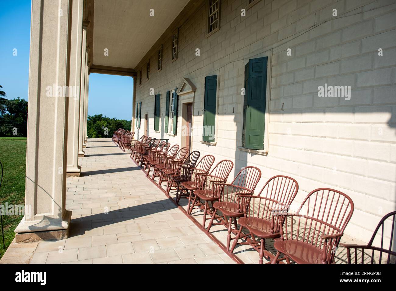 ALEXANDRIA, Virginia, Stati Uniti — Una fila di sedie Windsor fiancheggia il patio all'esterno dell'edificio principale di Mount Vernon, la casa storica di George Washington, ad Alexandria, Virginia. Le sedie sono rivolte verso gli ampi giardini della tenuta e il fiume Potomac oltre. Foto Stock