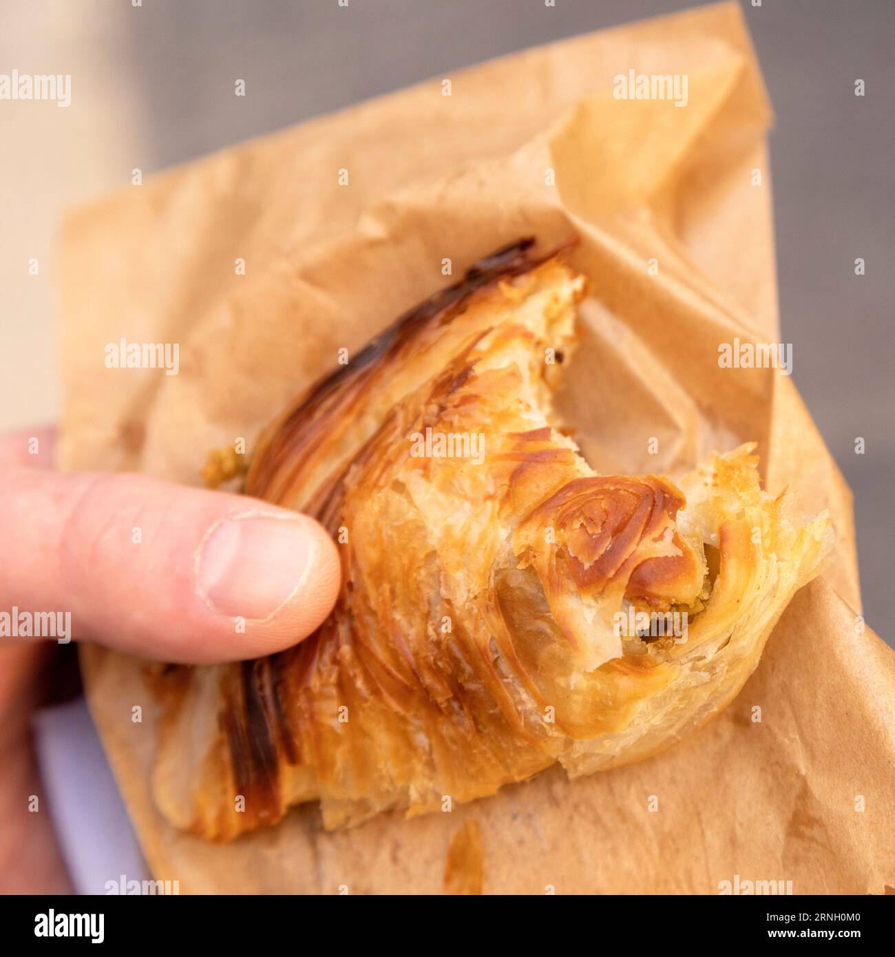 Una persona tiene un pasticcio ripieno di ricotta a la Valletta, Malta. I Pastizzi sono dolci saporiti che sono un popolare spuntino maltese. Foto Stock