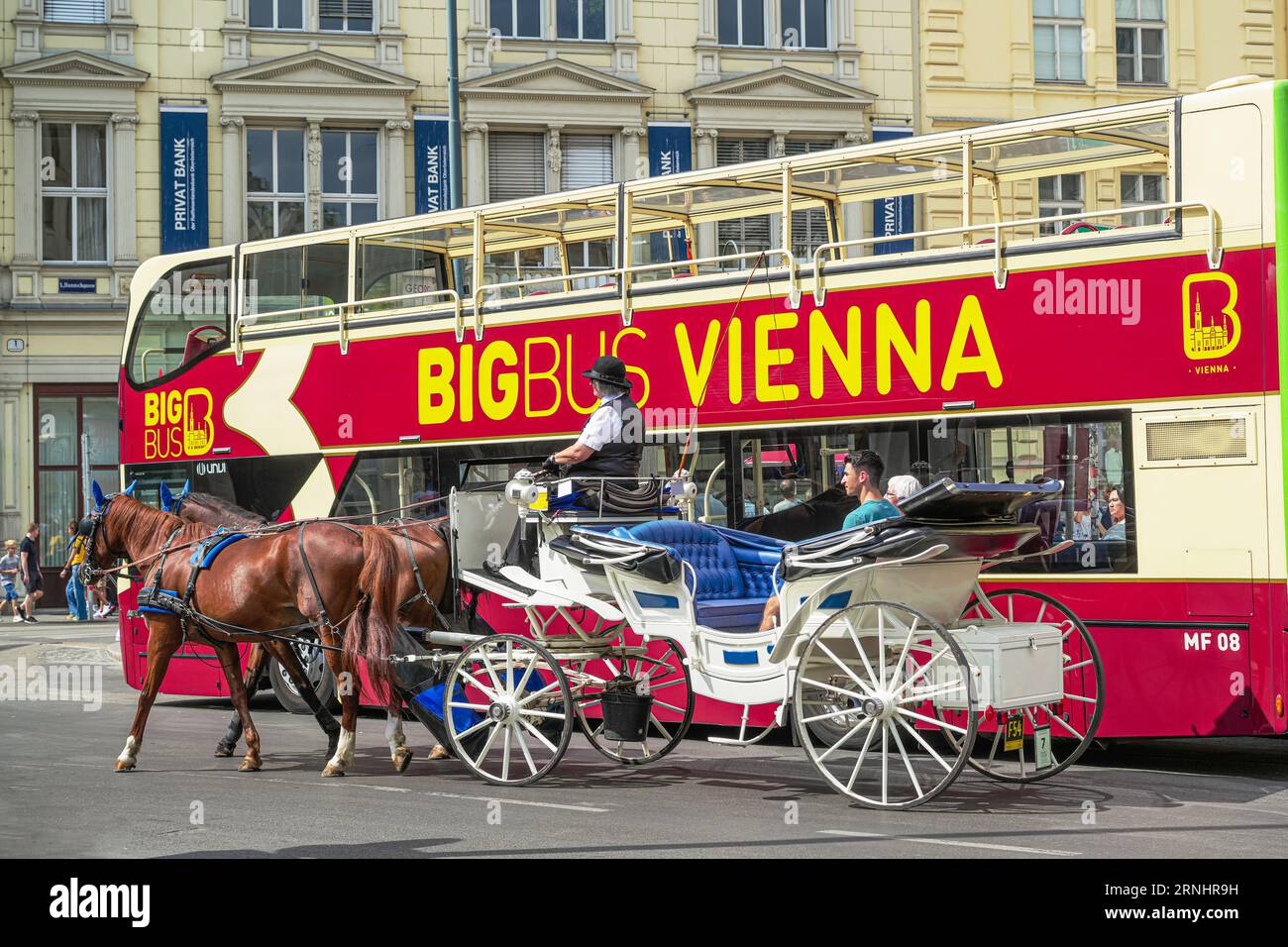 Vienna, Austria - 28 agosto 2023: Carrozza trainata da cavalli e autobus sono due mezzi di trasporto alternativi per un tour panoramico di Vienna Foto Stock