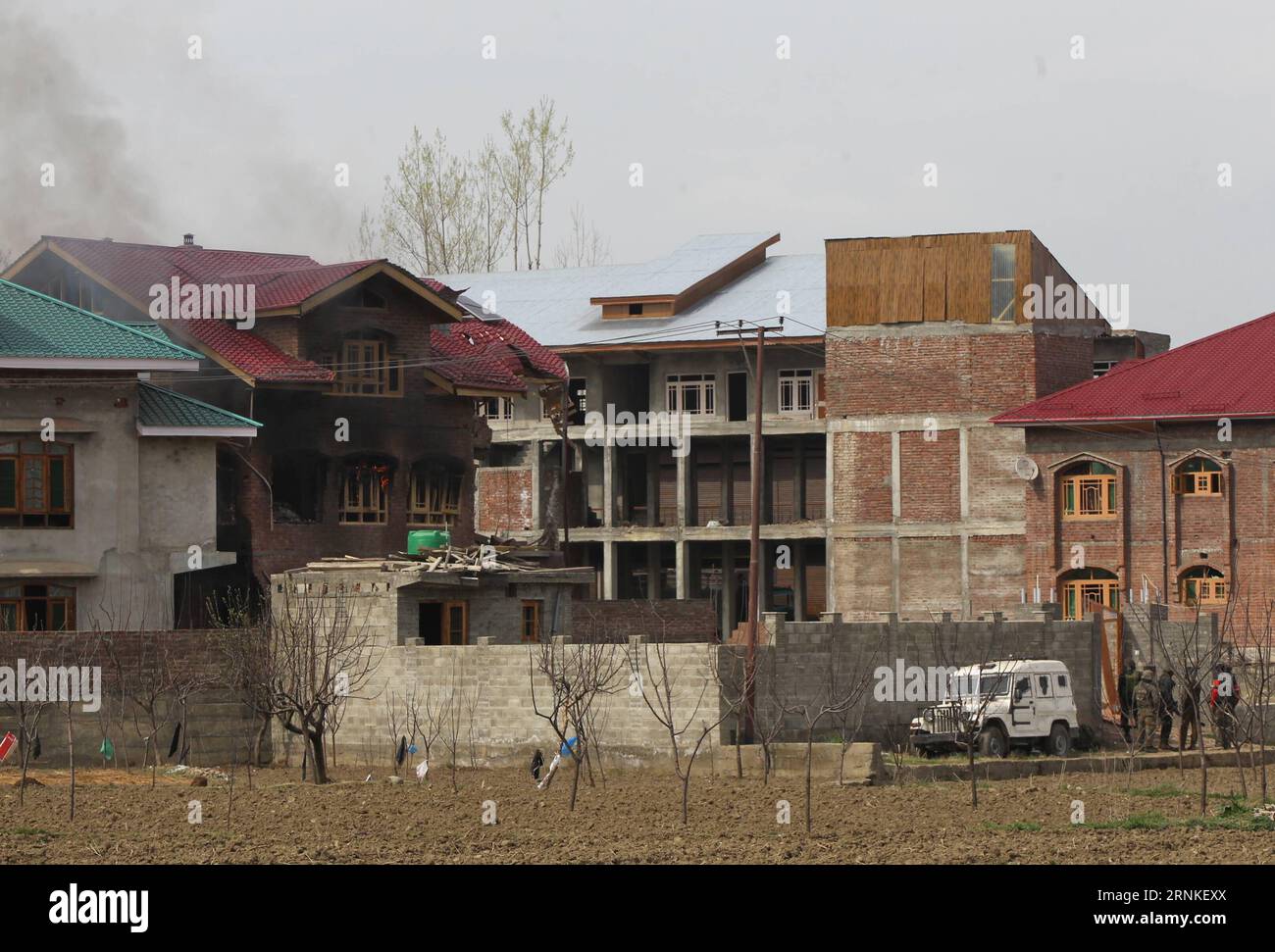 (170328) -- SRINAGAR, 28 marzo 2017 -- soldati e poliziotti dell'esercito indiano prendono posizione quando fumo e fiamme escono da una casa residenziale durante uno scontro a fuoco nel villaggio di Durbugh nel distretto di Chadoora di Budgam, a circa 22 km a sud della città di Srinagar, la capitale estiva del Kashmir controllato dagli indiani, il 28 marzo 2017. Almeno tre giovani sono stati uccisi e altri 13 feriti martedì dopo che le forze governative hanno sparato contro i manifestanti vicino a un sito di sparatorie nel Kashmir controllato dagli indiani, ha detto la polizia. ) (dtf) INDIA-KASHMIR-SRINAGAR-GUNFIGHT JavedxDar PUBLICATIONxNOTxINxCHN Srinagar marzo 28 2017 Indian A Foto Stock