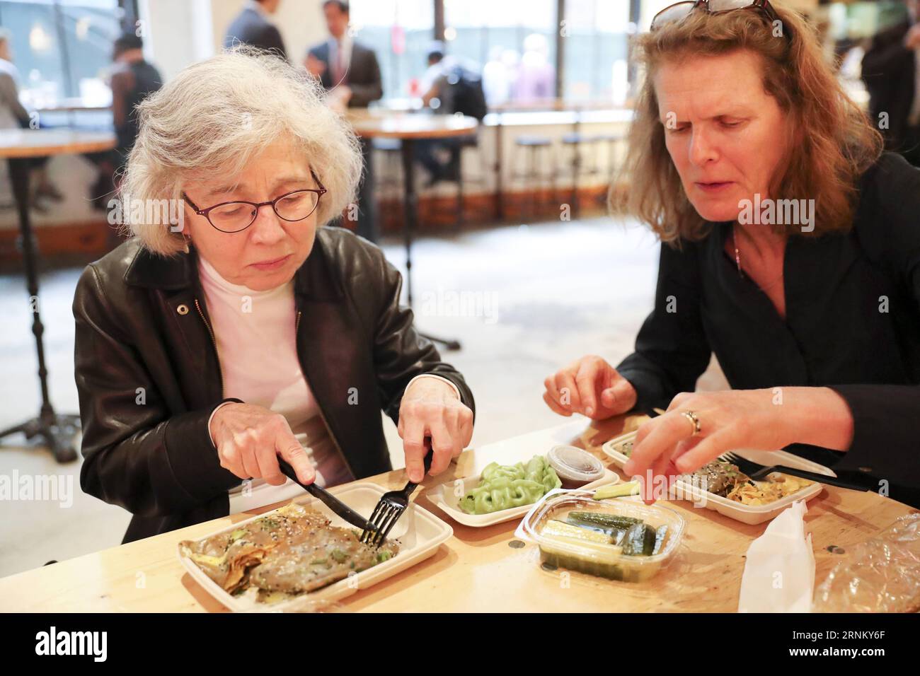 (170425) -- NEW YORK, 25 aprile 2017 -- i clienti mangiano Jianbing di Mr. Bing in UrbanSpace food Court a New York, Stati Uniti, 17 aprile 2017. UrbanSpace nel centro di New York è un luogo dove i collari bianchi vengono a pranzo durante i loro giorni lavorativi. Negli ultimi mesi, i clienti si sono sempre allineati prima di un chiosco sotto uno striscione con caratteri cinesi. Quello che questo chiosco vende è un autentico cibo cinese nel nord della Cina -- Jianbing, o crepe cinese. Il chiosco è marchiato Mr. Bing ed è di proprietà di Brian Goldberg, che è nato e cresciuto a New York. Goldberg è molto coinvolto con il cinese C. Foto Stock