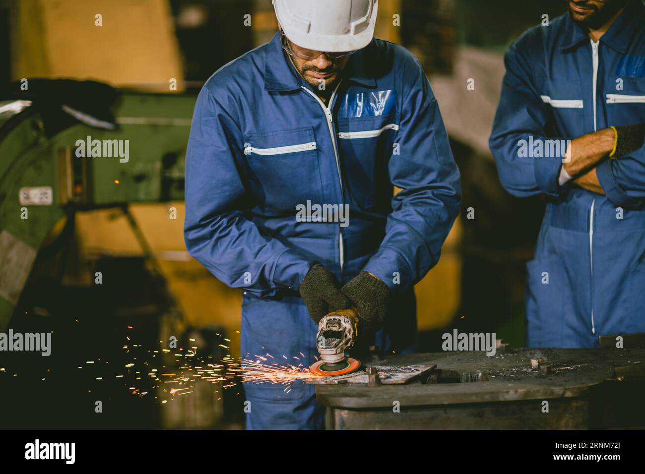 Lavoratore industriale che utilizza la smerigliatrice angolare e il taglio di una lamiera. Appaltatore in strutture metalliche per la produzione di uniformi di sicurezza e elmetti.industria pesante Foto Stock