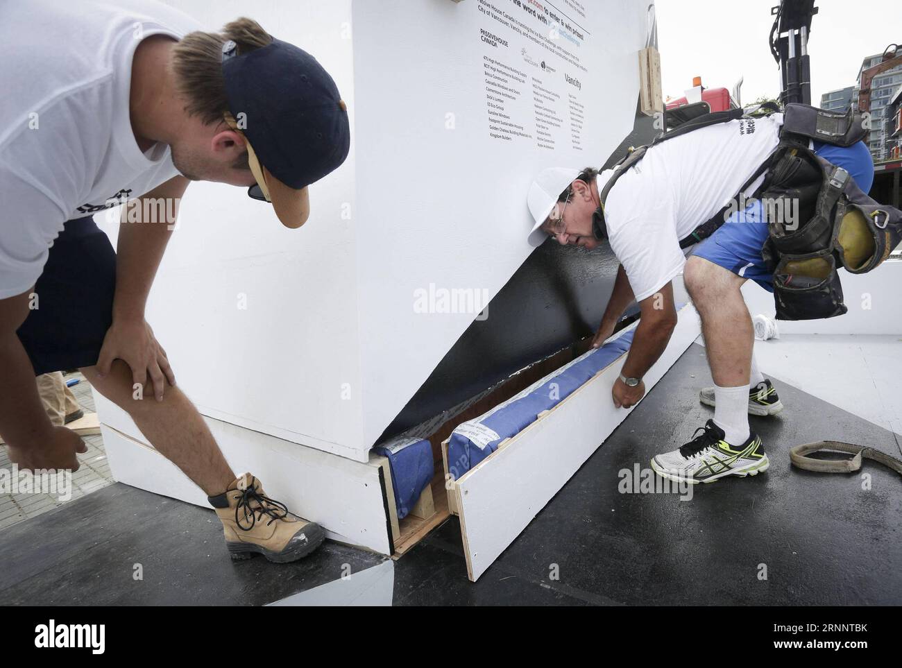 (170728) -- VANCOUVER, 28 luglio 2017 -- i lavoratori installano una struttura di scatole di ghiaccio isolanti durante la Ice Box Challenge a Vancouver, Canada, 27 luglio 2017. La Ice Box Challenge è un esperimento pubblico volto a dimostrare i vantaggi degli edifici ad alta efficienza energetica secondo lo standard di costruzione delle abitazioni passive. Due piccole scatole simili a quelle di una casa costruite con standard passiva e specifiche del codice edilizio locale che si trovano fianco a fianco sotto un'area aperta per 18 giorni con un blocco di ghiaccio da una tonnellata incassato per testimoniare il nuovo standard edilizio a emissioni zero. ) CANADA-VANCOUVER-ICE BOX SFIDA LIANGXSE Foto Stock