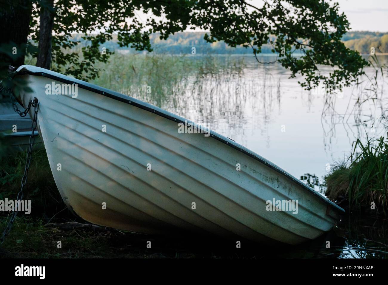 Kirkkonummi / FINLANDIA - 1° SETTEMBRE 2023: Una piccola barca a remi spiaggiò il lago durante il tramonto. Foto Stock