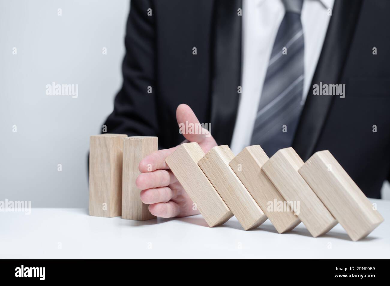 Blocchi di legno sotto protezione mani uomo d'affari, domino, concetto di sicurezza assicurativa Foto Stock