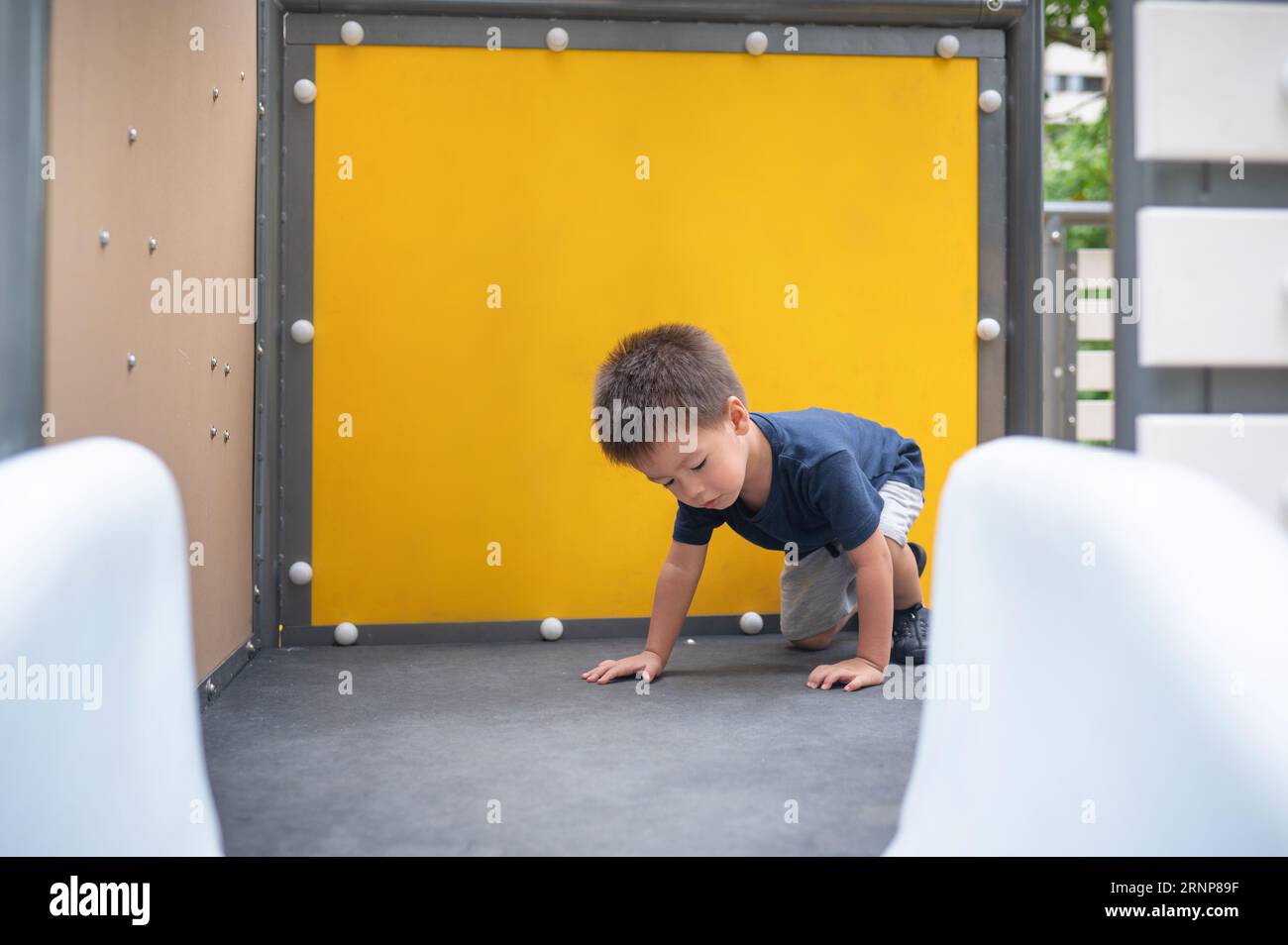 Un simpatico bambino di due anni si sta divertendo a esplorare i giocattoli del parco Foto Stock