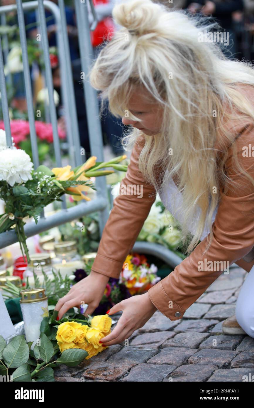 (170819) -- TURKU, 19 agosto 2017 -- Una donna mette un bouquet per commemorare le vittime delle pugnalate del venerdì nella piazza del mercato di Turku, Finlandia, il 19 agosto 2017. Altri quattro marocchini sono stati arrestati e un mandato è stato emesso per un quinto dopo che un giovane ha pugnalato persone nelle piazze della città finlandese sud-occidentale di Turku, ha detto la polizia sabato. ) (Zjl) FINLAND-TURKU-STABBING-MEMORIAL ZhangxXuan PUBLICATIONxNOTxINxCHN Turku 19 agosto 2017 una donna mette un mazzo per commemorare le vittime dei pugnalamenti del venerdì nella piazza del mercato di Turku Finlandia IL 19 agosto 2017 altri quattro idylen na Foto Stock