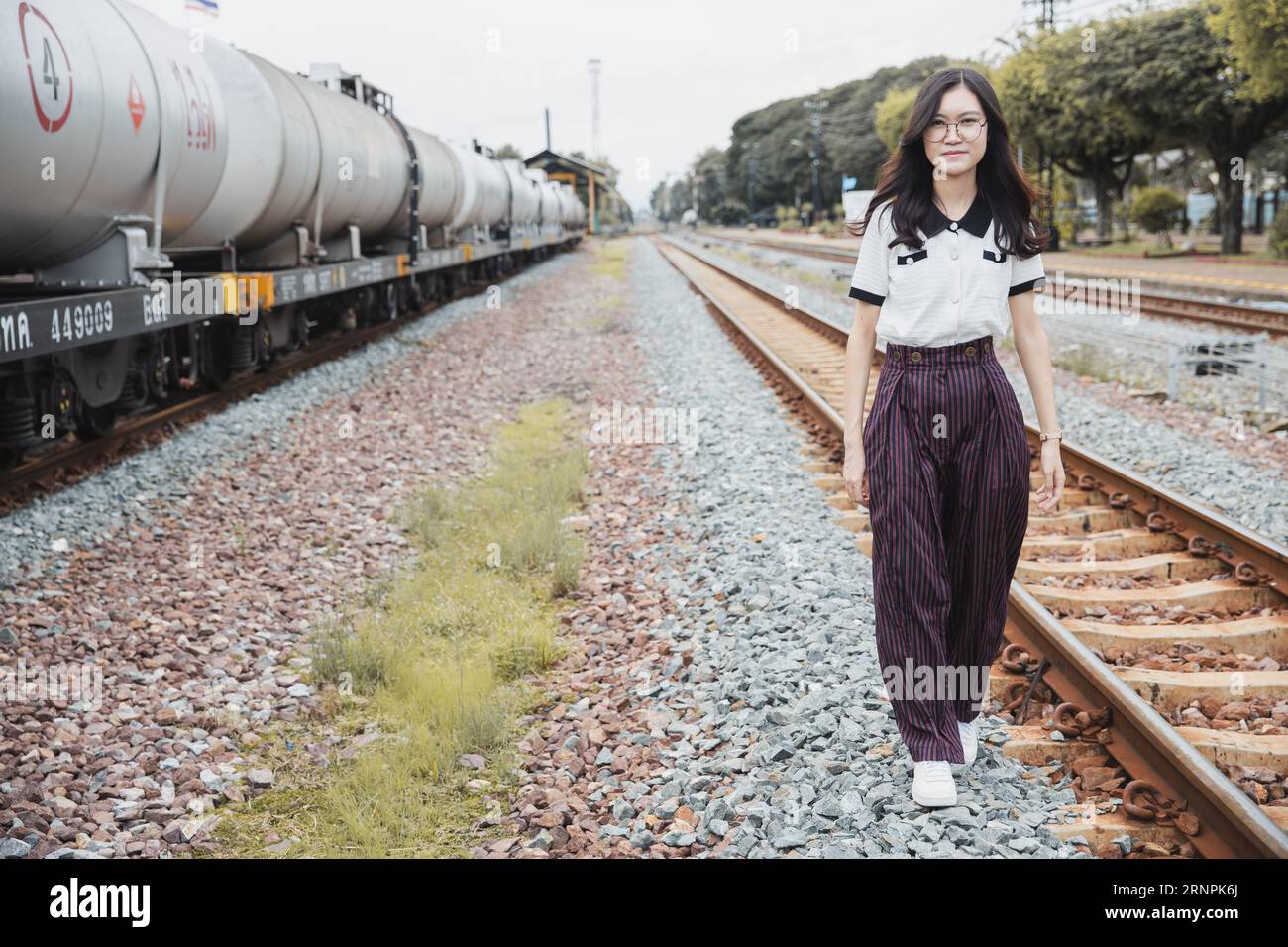 ritratto donna asiatica felice sulla stazione ferroviaria industria delle locomotive tempo libero rilassarsi immagine sorriso Foto Stock