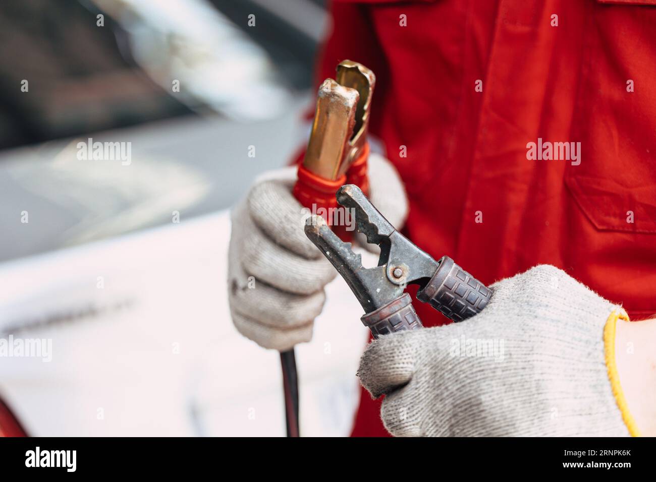 closeup maschio meccanico che fissa i morsetti della batteria impugnatura per caricare la batteria dell'auto in officina di riparazione automatica Foto Stock