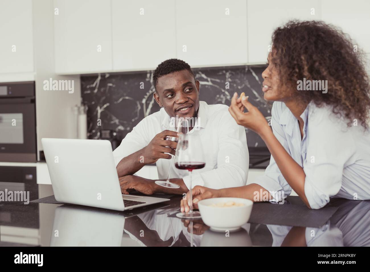 I neri sposano vino bevono datteri chiacchierando insieme rilassarsi incontrarsi in cucina, casa, colori vintage Foto Stock