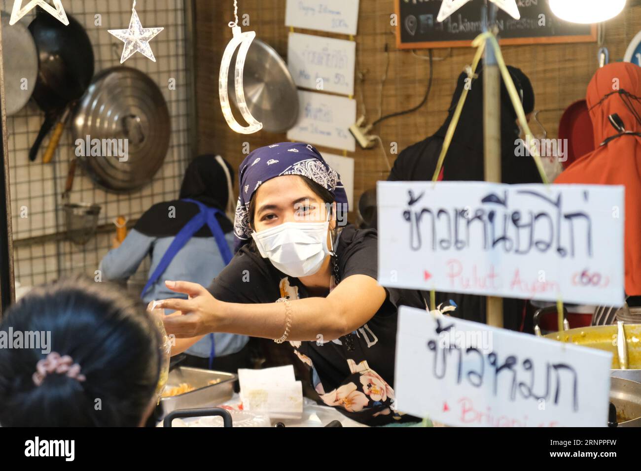 Stallholder musulmano che vende cibo halal al vivace e trendy mercato Chatuchak di Bangkok Foto Stock
