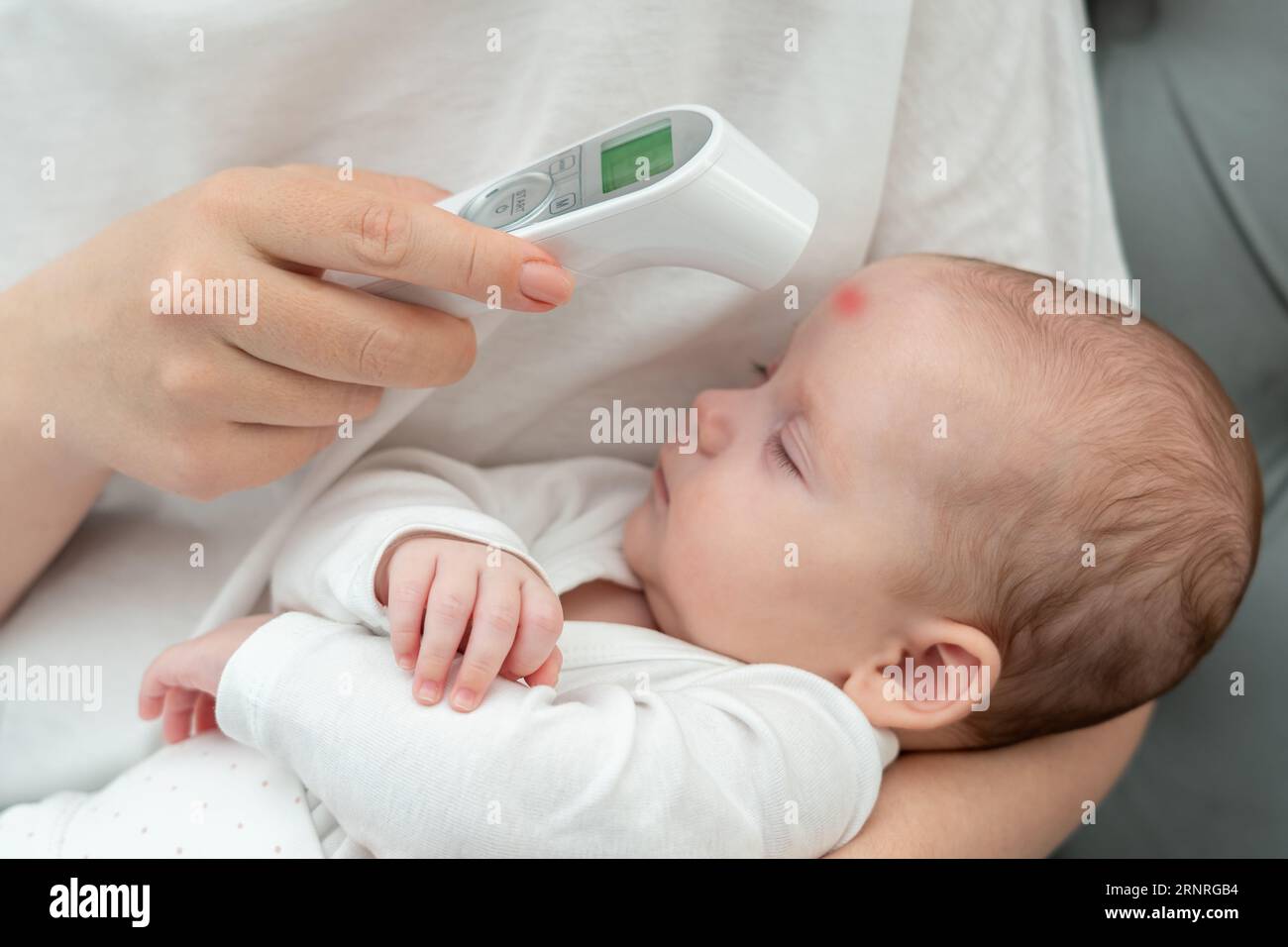 Garantire il benessere del neonato con lo strumento elettronico. Concetto di cura materna e precisione Foto Stock