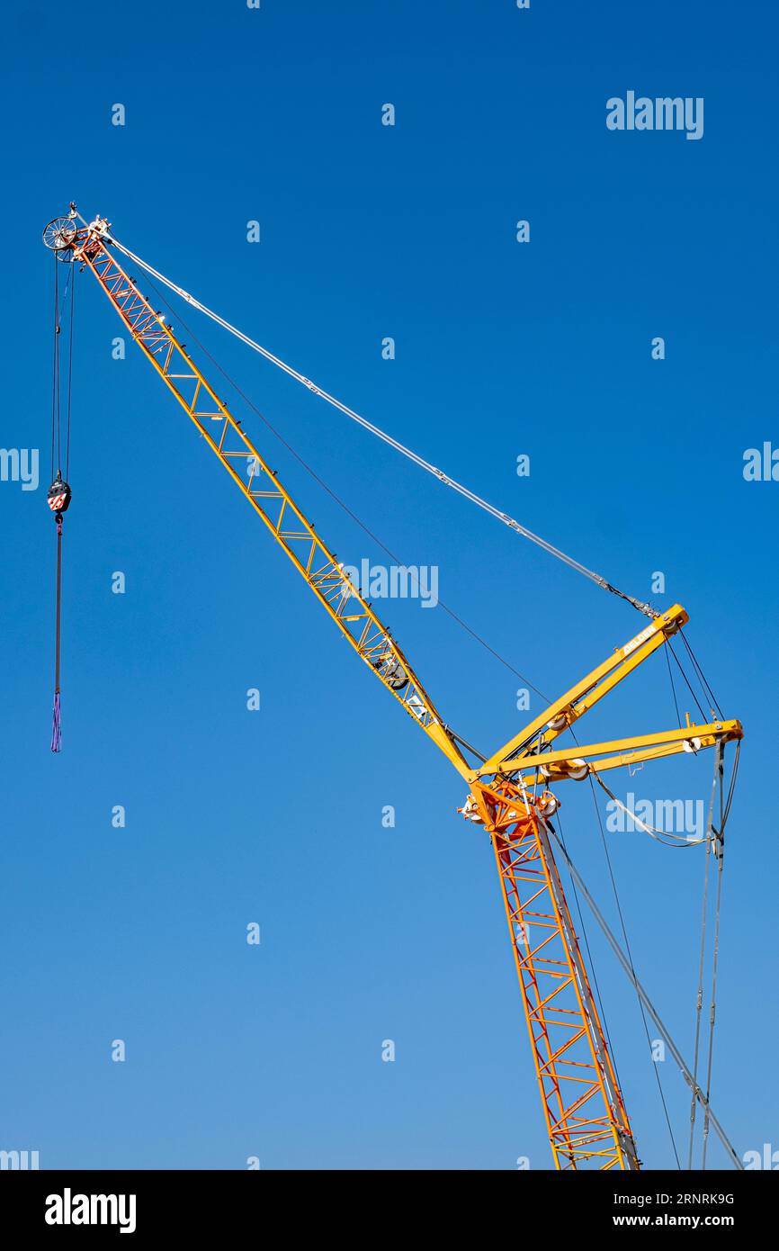 Particolare della gru da costruzione sul cantiere, isolata contro il cielo blu. Foto Stock