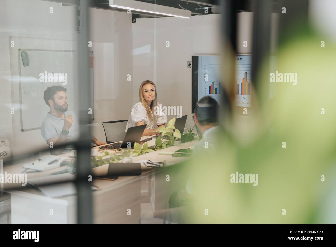 Un team diversificato di professionisti aziendali che analizza le statistiche di vendita, pianifica i progetti e lavora insieme in un ambiente di ufficio. Foto Stock