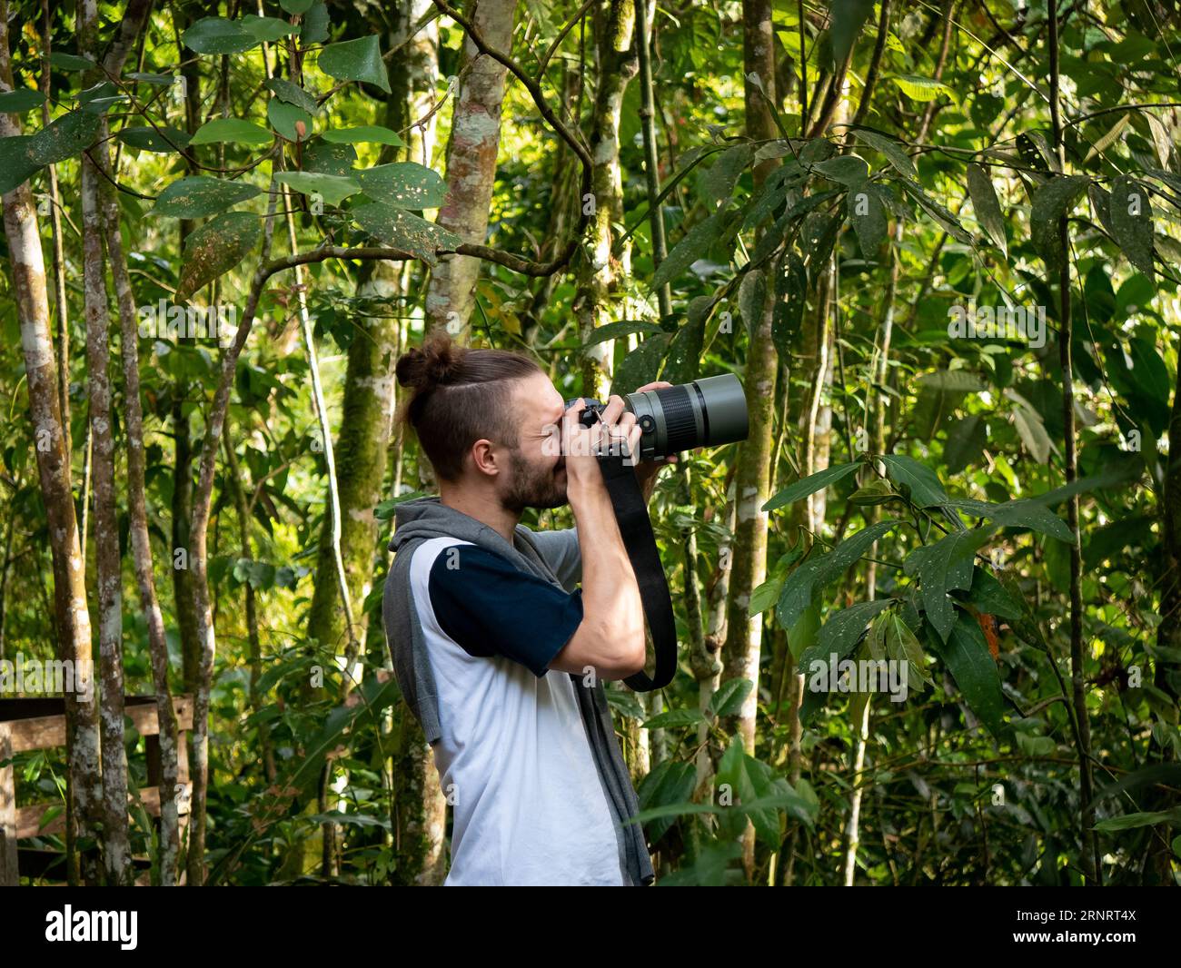 Il giovane fotografo bianco cerca di fotografare gli uccelli nel mezzo della natura Foto Stock