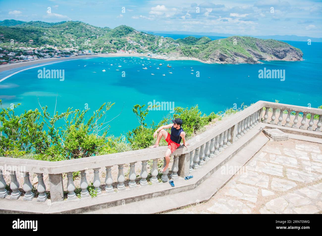Buon turista seduto in un punto panoramico di una baia. Ritratto di turista nella vista della baia di San Juan del Sur. Promozione viaggi e turismo Foto Stock