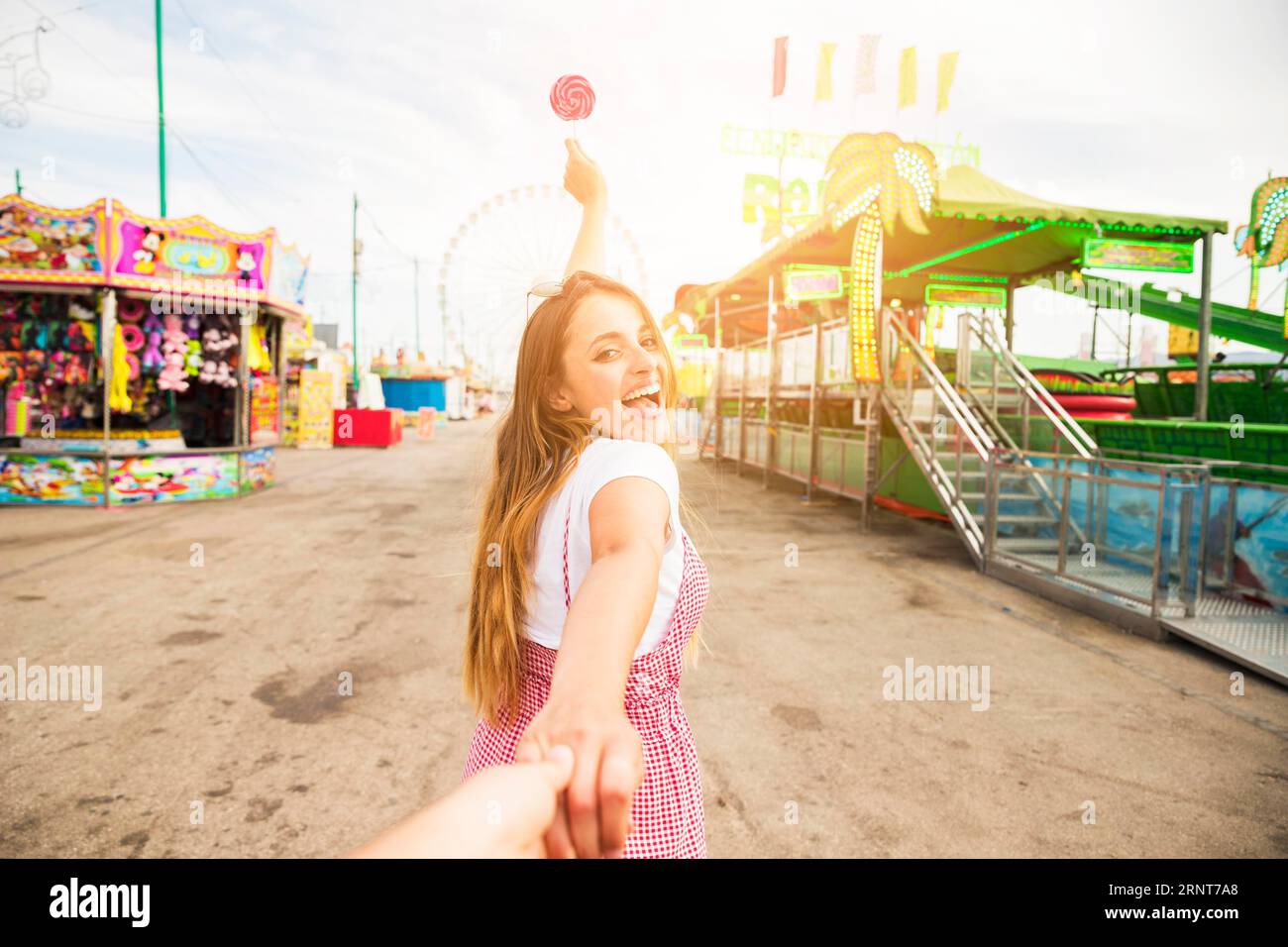 Giovane donna che conduce il suo amico tenendo un parco divertimenti Lollipop Foto Stock