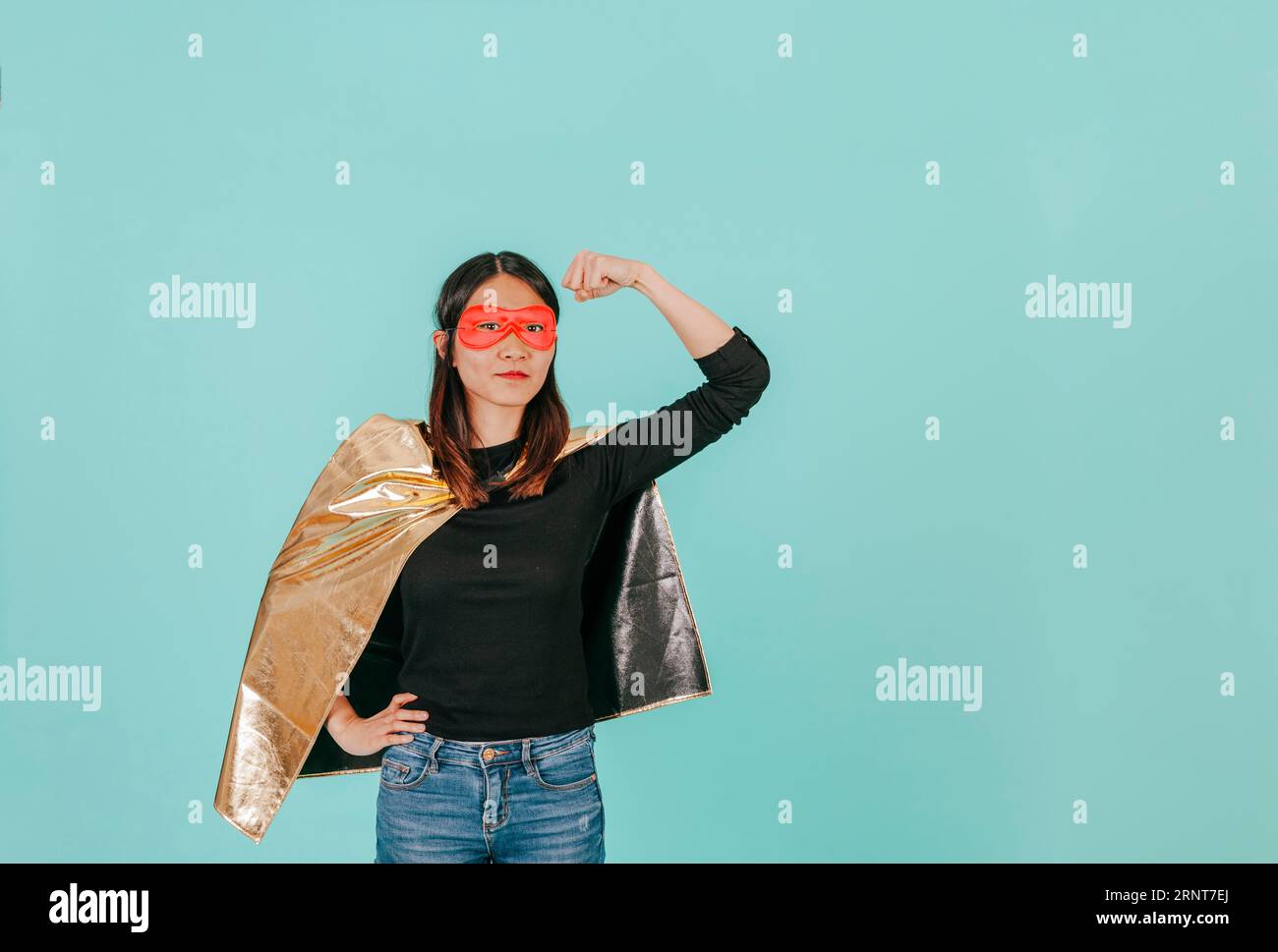 Costume da supereroe donna asiatica che mostra bicipiti Foto Stock
