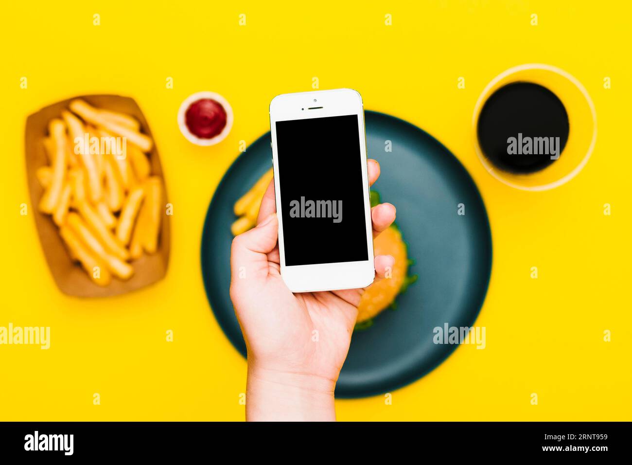 Base piatta che regge la piastra dello smartphone con hamburger Foto Stock