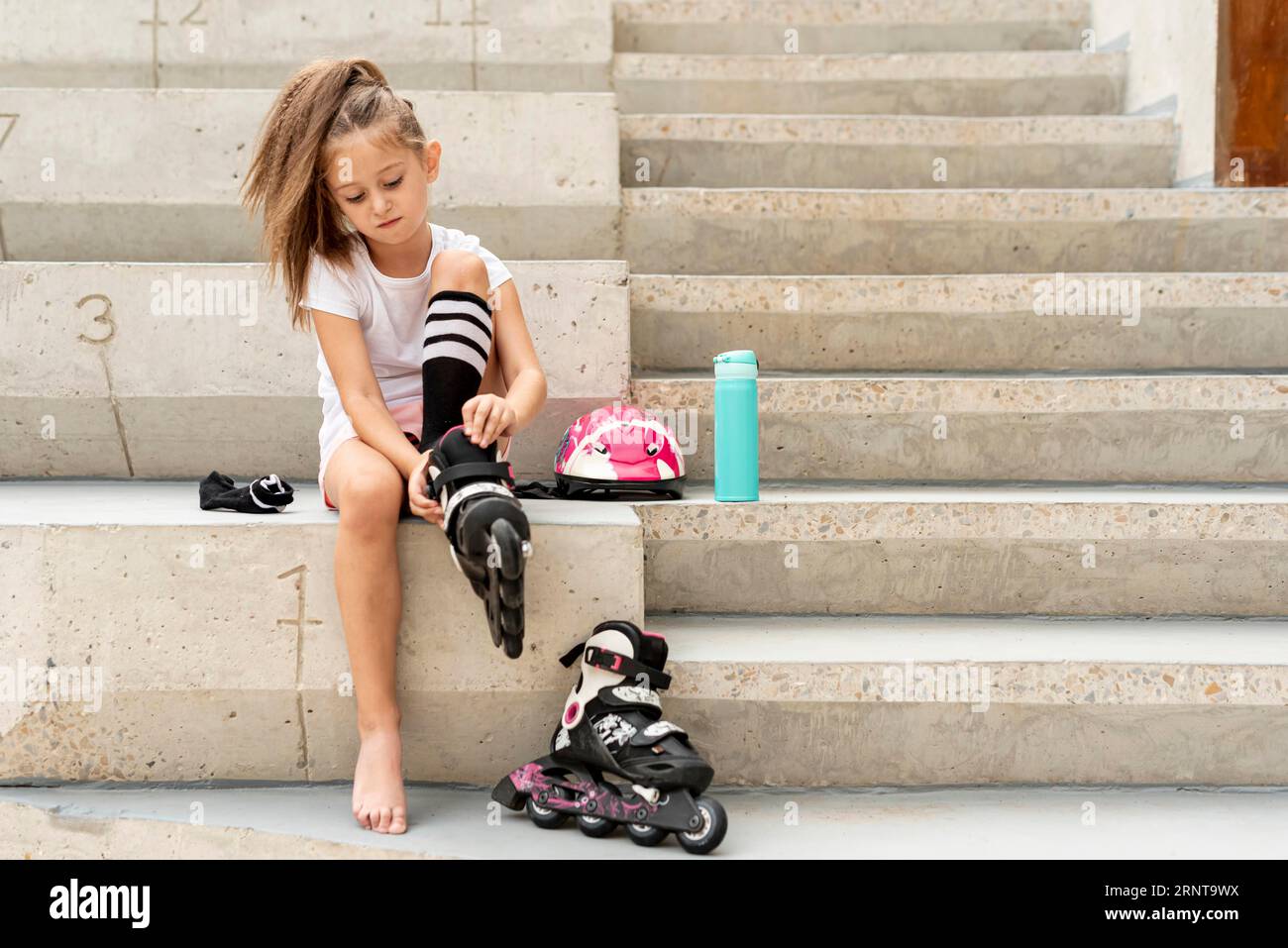 Ragazza che mette lame nere a rullo Foto Stock