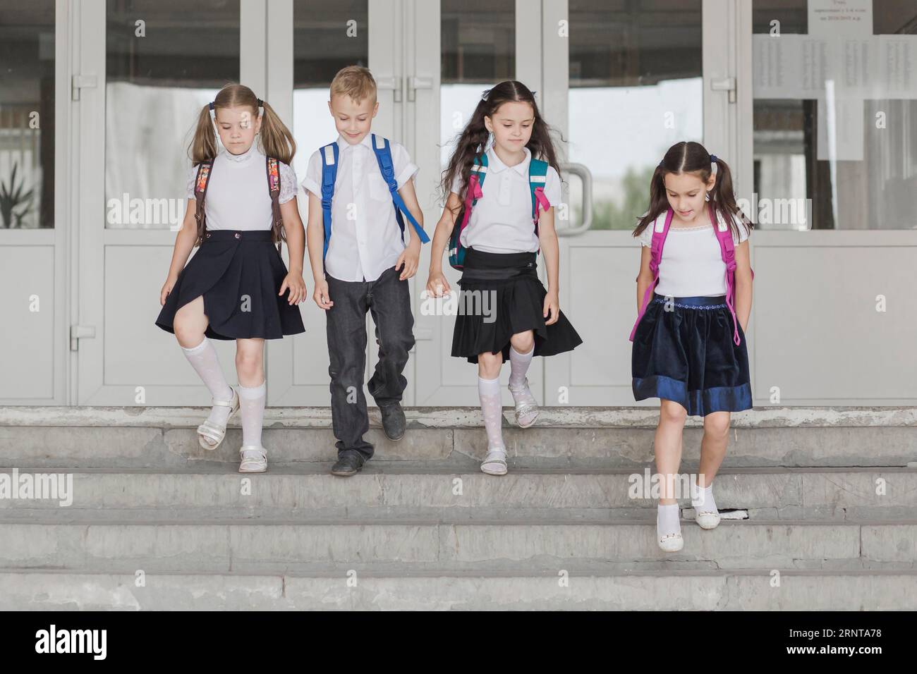Bambini che camminano lungo i gradini della scuola Foto Stock